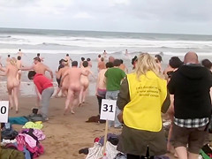 Hundreds of nudist people running into the sea naked