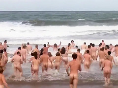 Hundreds of nudist people running into the sea naked