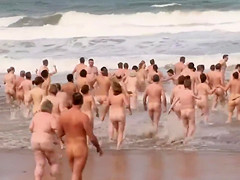Hundreds of nudist people running into the sea naked