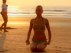 Bald beauty doing yoga by the sea