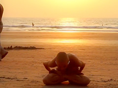 Bald beauty doing yoga by the sea