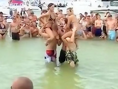 Sexy beach girls fighting each other from the shoulders of their boyfriends
