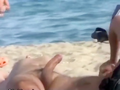 Wife strokes his half hard penis at the beach