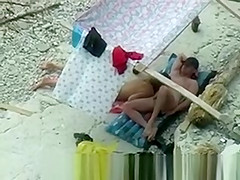 Nudist couple spied on beach.