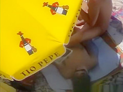 Nudists having sex under the sun umbrella