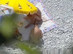 Nudists having sex under the sun umbrella