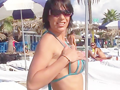 Hot brunette milf posing in sexy bikini on public beach