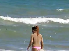 Topless legal age teenager playing at beach in water