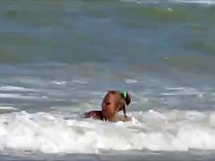 Topless legal age teenager playing at beach in water