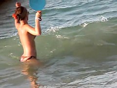 Topless girl playing on the beach and getting voyeured