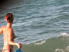 Topless girl playing on the beach and getting voyeured