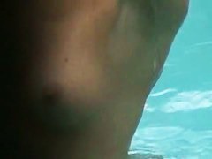 Gorgeous blonde with juicy tits swims completely naked in the pool by the beach