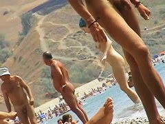 Foxy brunette in a blue bottom bikini and flippers on a nude beach