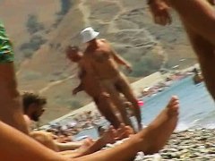 Foxy brunette in a blue bottom bikini and flippers on a nude beach