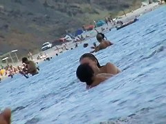 Foxy brunette in a blue bottom bikini and flippers on a nude beach