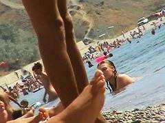 Foxy brunette in a blue bottom bikini and flippers on a nude beach