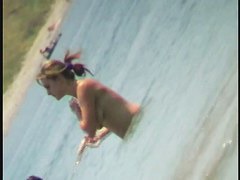 Nudist video at the beach has shy girl playing in the water