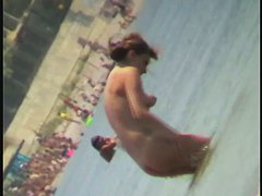 Nudist video at the beach has shy girl playing in the water