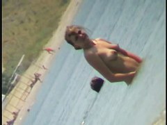 Nudist video at the beach has shy girl playing in the water