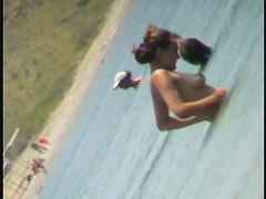 Nudist video at the beach has shy girl playing in the water