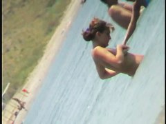 Nudist video at the beach has shy girl playing in the water