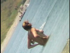 Nudist video at the beach has shy girl playing in the water