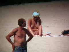 Horny naked brunette woman teasing her mates on the beach