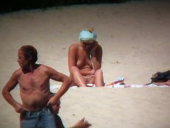 Horny naked brunette woman teasing her mates on the beach