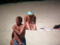 Horny naked brunette woman teasing her mates on the beach