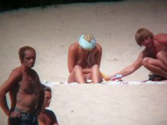 Horny naked brunette woman teasing her mates on the beach