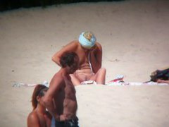 Horny naked brunette woman teasing her mates on the beach