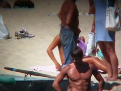 Horny naked brunette woman teasing her mates on the beach