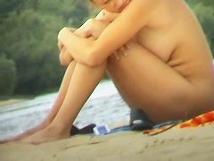 Naked chick on the beach, sitting with her arms over her legs porno