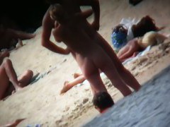 A voyeur beach video of a nude couple standing in the water