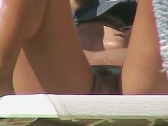 Oiled babe with trimmed vagina taking sunbaths on the beach