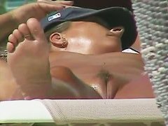 Oiled babe with trimmed vagina taking sunbaths on the beach