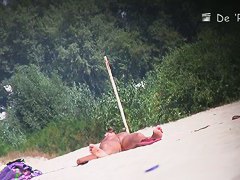 Nude beach voyeur shot of two hot brunettes sunbathing