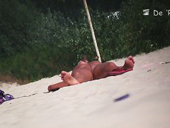 Nude beach voyeur shot of two hot brunettes sunbathing