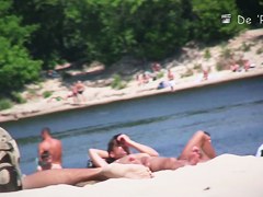 Girl is covering nude tits with hands on beach voyeur cam