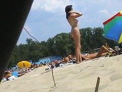 Spy camera on a nudist beach focuses on a sexy brunette