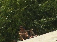Spy camera on a nudist beach focuses on a sexy brunette