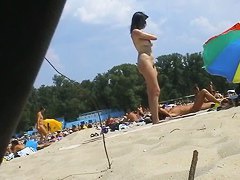 Spy camera on a nudist beach focuses on a sexy brunette