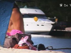 Babe with small tits and shaved vagina relaxes on the beach