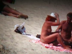 Mature blonde spreading her shaved pussy on the beach