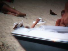 Mature blonde spreading her shaved pussy on the beach