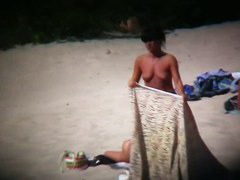 Nudist beach with dressed gentlemen and topless ladies