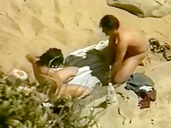 Un couple naturiste se touche et elle suce sur la plage