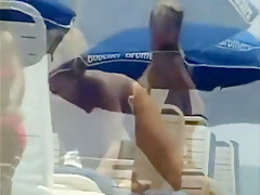 De belles femmes en bikini ou topless sur le sable fin