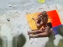 Il tripote une jeune nana à la plage devant son épouse
