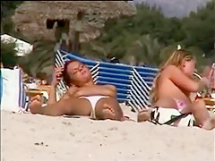 Deux copines topless simulent de baiser sur la plage